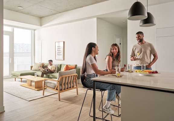 A group of people are gathered around a kitchen island.