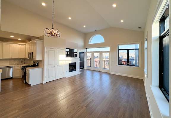 Spacious open-concept kitchen and living area at Highpoint West Town apartments in Chicago with fireplace, hardwood floors, balcony access, and abundant natural light