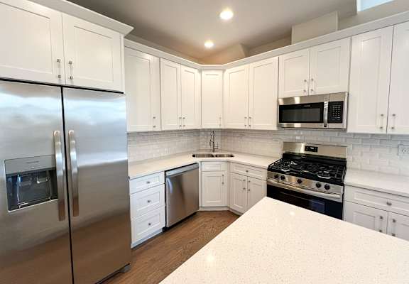 Modern kitchen at Highpoint West Town apartments in Chicago with white cabinetry, stainless steel refrigerator, and sleek finishes