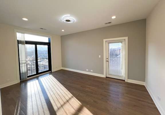 Primary bedroom at Highpoint West Town apartments in Chicago with Juliet balcony, outdoor patio access, and large windows for natural light