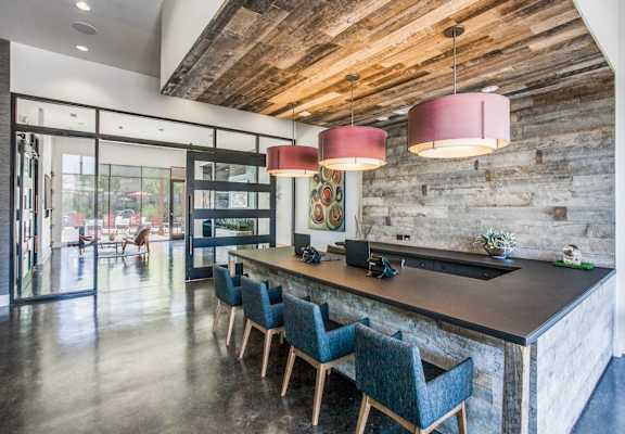 A modern kitchen with a wooden ceiling and a long island with chairs.at Infinity on Yorktown, Dallas, TX 75208