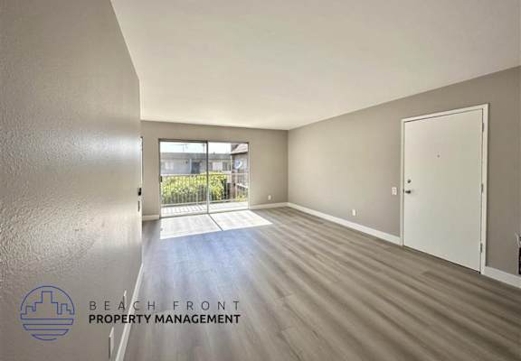 an empty living room with wood flooring and a door to a patio