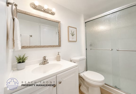 A bathroom with a white toilet, sink, and mirror.