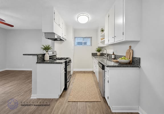 A kitchen with white cabinets and a black countertop.