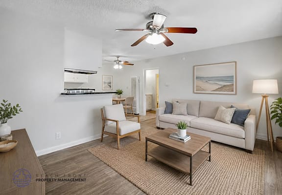 A living room with a ceiling fan, a couch, a chair, and a coffee table.