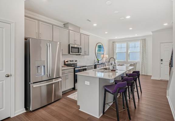 Modern kitchen with bar seating and open dining space at The Maple townhomes Raleigh NC