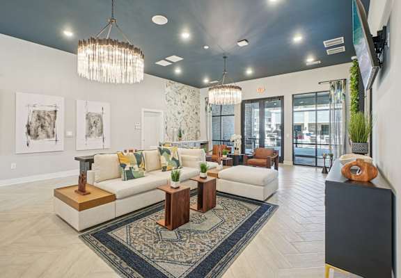 A living room with a white couch, a rug, and a chandelier.