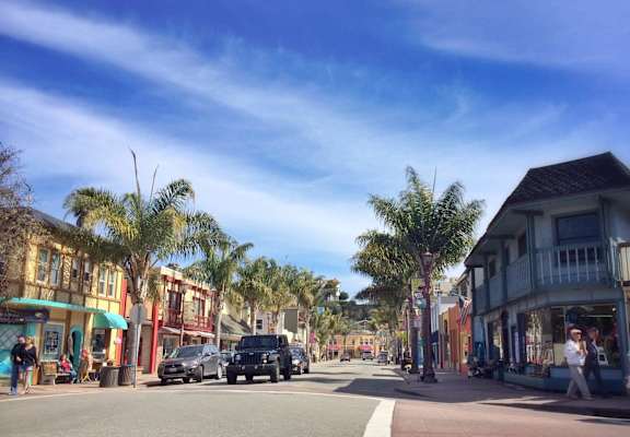 A street scene with cars and palm trees.