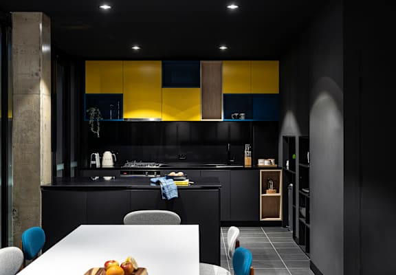a black kitchen with yellow cabinets and a white table and chairs
