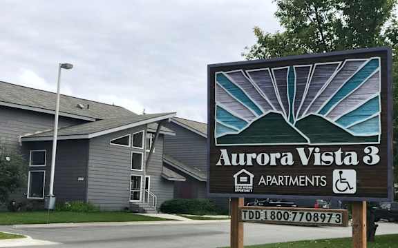 A sign for Aurora Vista 3 Apartments with a TDD number on it.