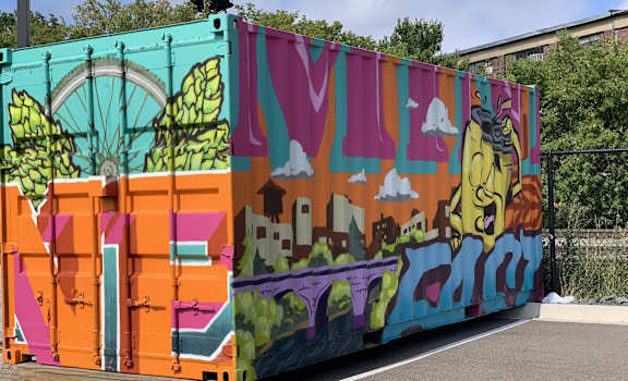 A colorful artwork on a wall with a person walking by.