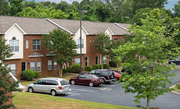 a parking lot in front of an apartment building with cars parked in the parking lot