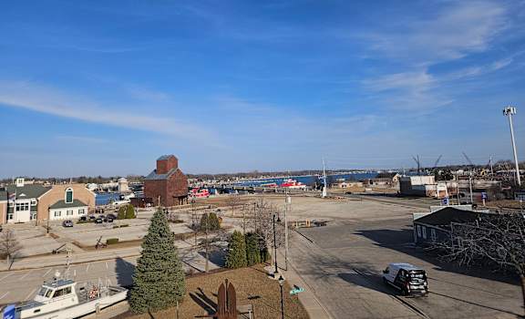 A view of a parking lot with a boat and a building in the background.