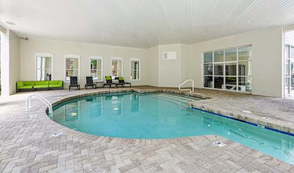 A large indoor swimming pool with a tiled floor and a bench.