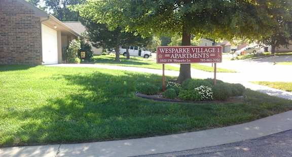 a sign in front of a lawn with a tree