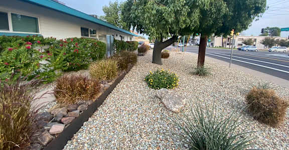 A gravel path leads to a white house with a green roof.