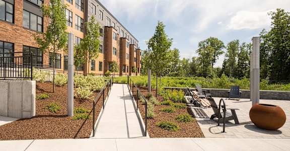 a courtyard with benches and trees in front of a brick building