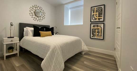 A bedroom with a white bed and a mirror on the wall.