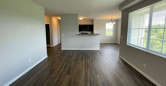 A spacious living room with wood flooring and a large window.