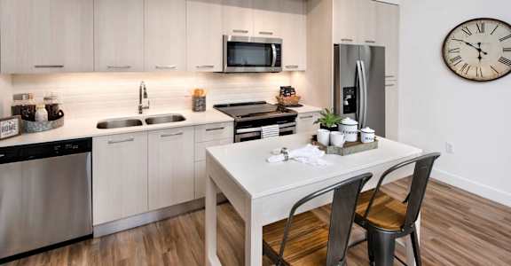 A modern kitchen with a white table and chairs.