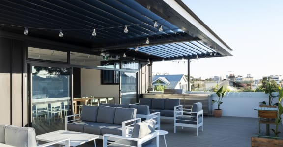 a roof terrace with couches and chairs and a blue and white shade canopy