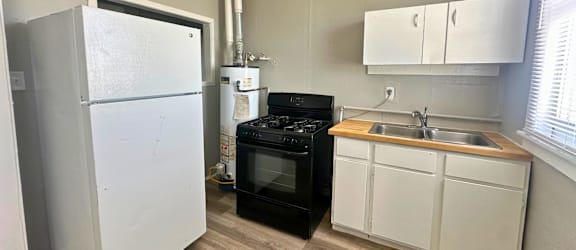A small kitchen with a black oven and white cabinets.