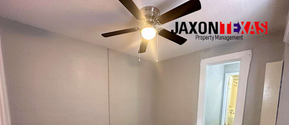 A room with a ceiling fan and wooden flooring.