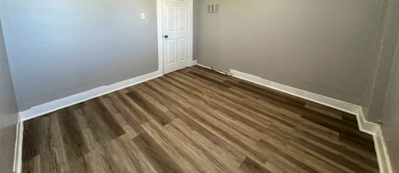 A room with a white door and wooden flooring.