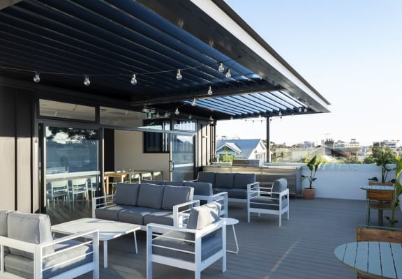 a roof terrace with couches and chairs and a blue and white shade canopy