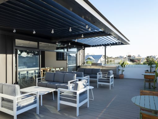 a roof terrace with couches and chairs and a bar with awning