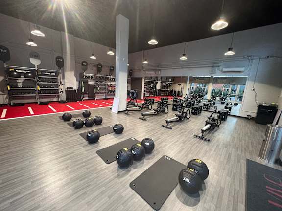A gym with a variety of equipment including dumbbells and weightlifting machines.