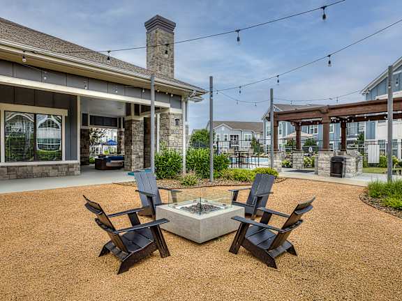 A patio with a fire pit and chairs.