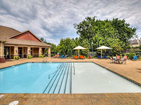 A large outdoor swimming pool with a diving board and lounge chairs.