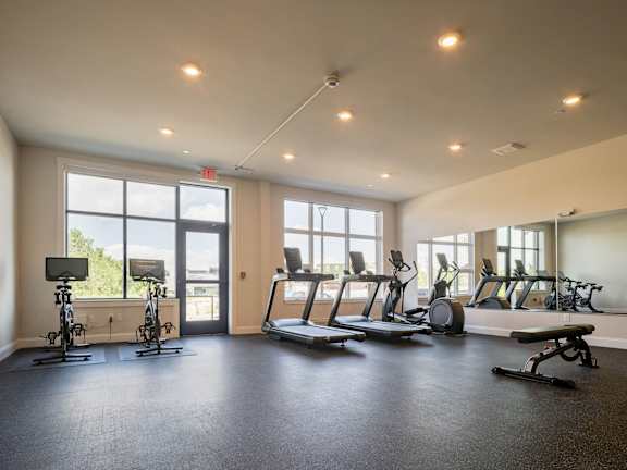 a gym with cardio equipment and windows in a building
