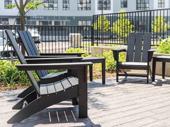 A black chair and table are on a wooden deck.