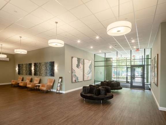 a large lobby with chairs and couches and a painting on the wall