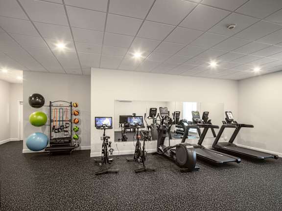 a gym with cardio equipment and weights in a room with white walls