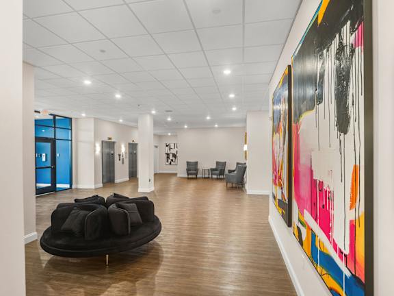 A large painting with black, pink, orange and yellow colors hangs on the wall.