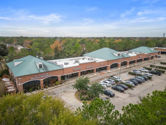 a large brick building with a green roof and a parking lot full of cars
