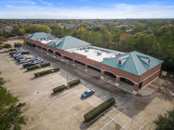 a brick building with a green roof and a parking lot with cars