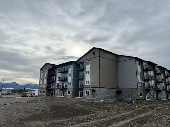 an apartment building on the side of a road under a cloudy sky