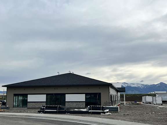 A building with a grey roof and a mountain in the background.