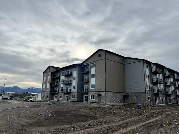 an apartment building on the side of a road under a cloudy sky