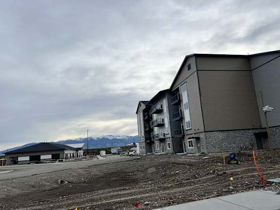 an empty parking lot next to an apartment building with mountains in the background