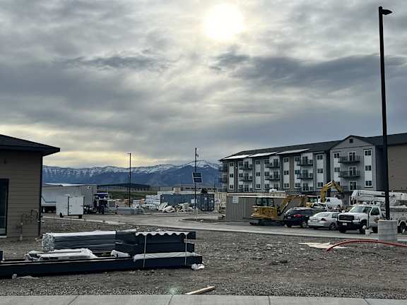 a construction site with cars and buildings and a cloudy sky