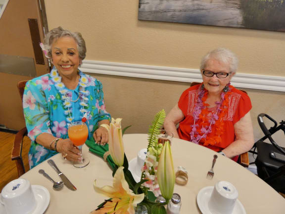 two women sitting at a table with a glass of orange juice