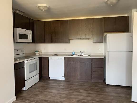A kitchen with white appliances and brown cabinets.