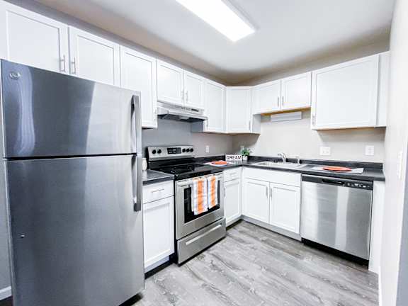 A kitchen with a stainless steel refrigerator and white cabinets.