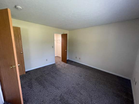A room with a carpeted floor and a doorway leading to another room.