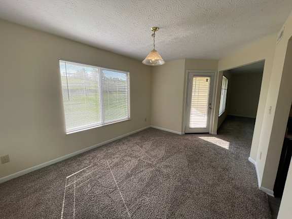 A room with a carpet floor and a window with blinds.